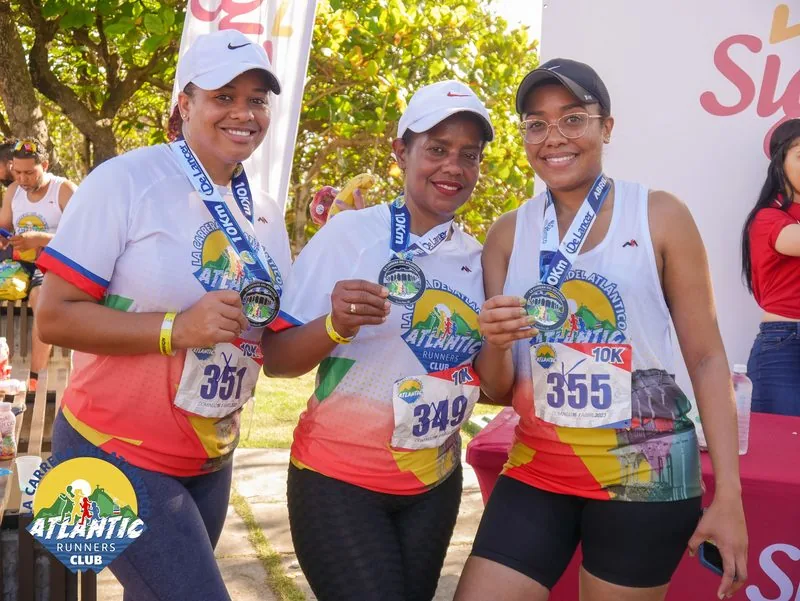 Tres atletas con medallas y bibs celebran su participación en una carrera atlética.