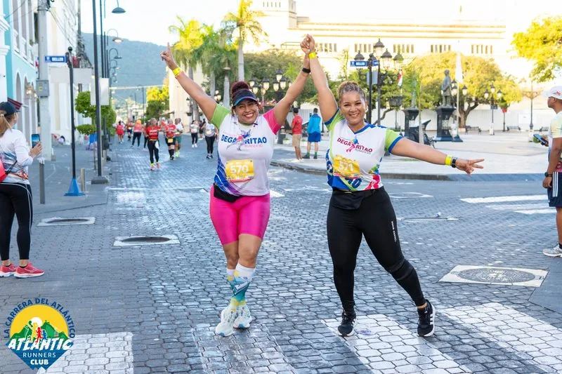 Dos atletas con bibs celebran juntos en una carrera urbana.