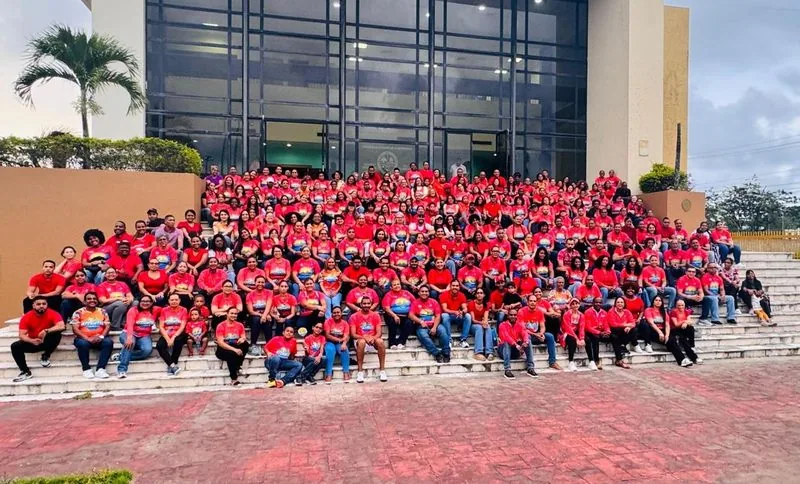 Un grupo numeroso de atletas en camisetas rojas posando para una foto en las escaleras de un edificio.
