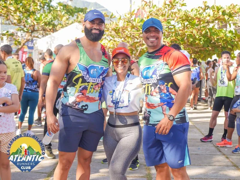 Tres atletas sonrientes posan juntos en una carrera atlética.