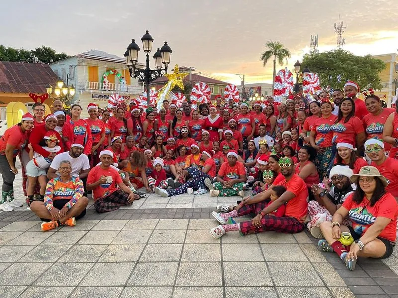 Un grupo numeroso de atletas vestidos con ropa roja y sombreros de Navidad posando para una foto en un entorno festivo.