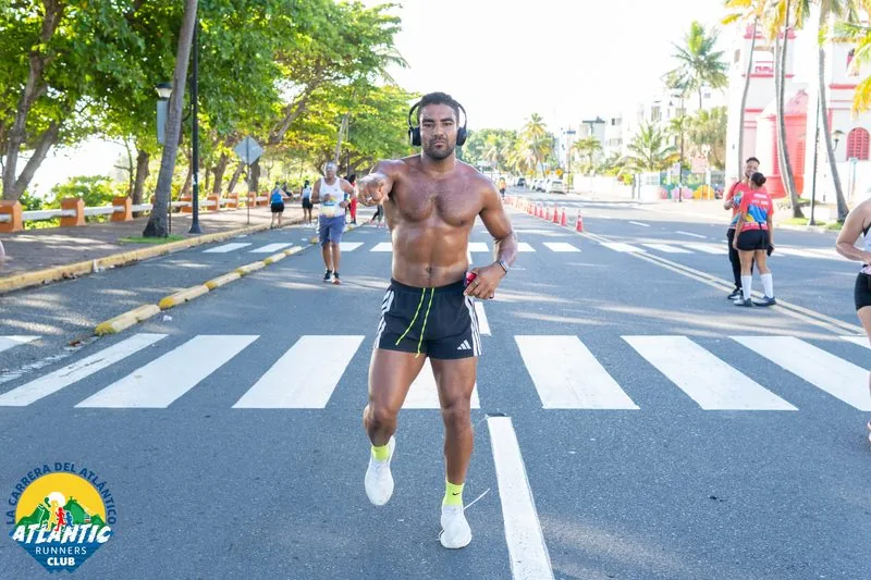 Un corredor sin camisa corre con energía en una carrera de atletismo en la República Dominicana.