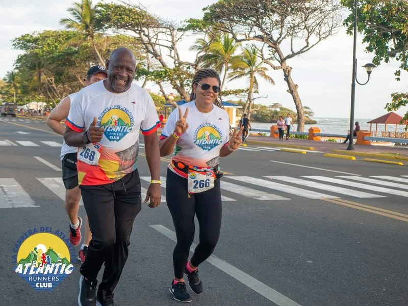 Diversos atletas en una carrera costera con palmeras y el mar al fondo.