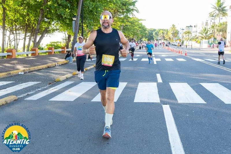 Un corredor en una carrera con un atuendo deportivo y un número de participación en el pecho.