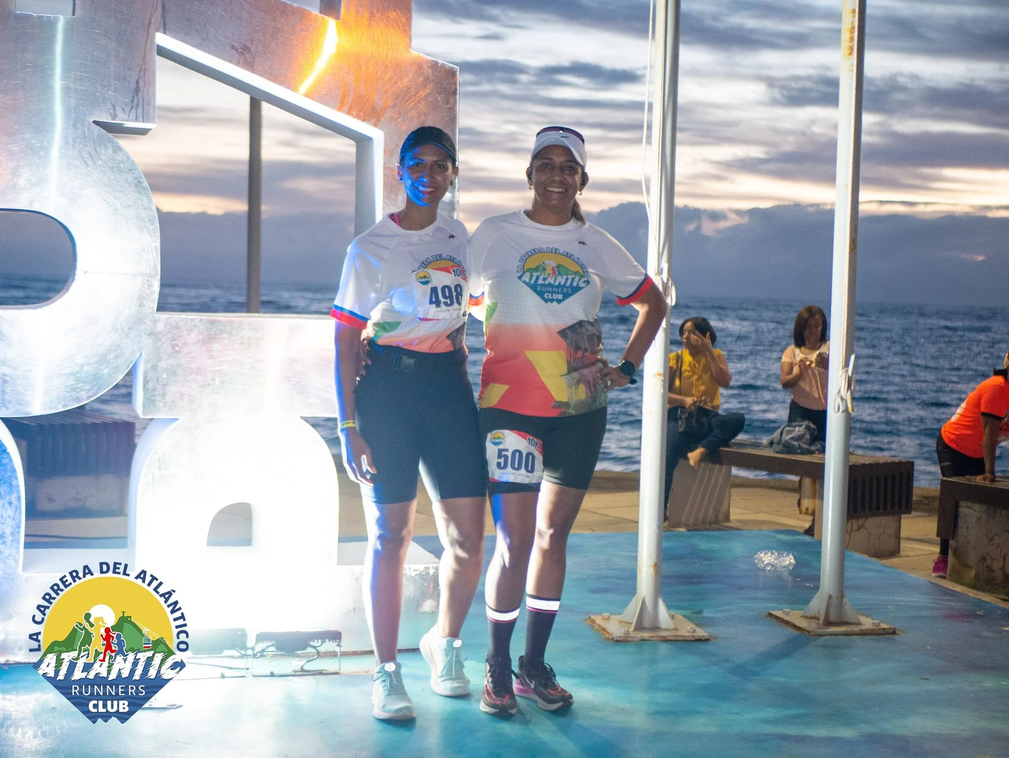 Dos atletas con bibs de carrera posan en la línea de salida de la Carrera del Atlántico.